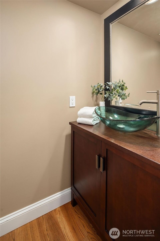 bathroom with baseboards, wood finished floors, and vanity