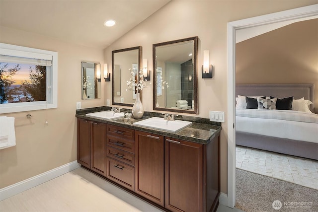 ensuite bathroom featuring lofted ceiling, double vanity, ensuite bathroom, and a sink