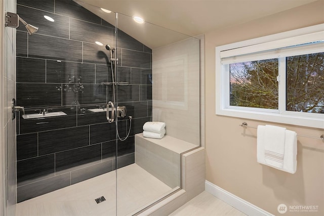 bathroom featuring a stall shower, baseboards, and vaulted ceiling