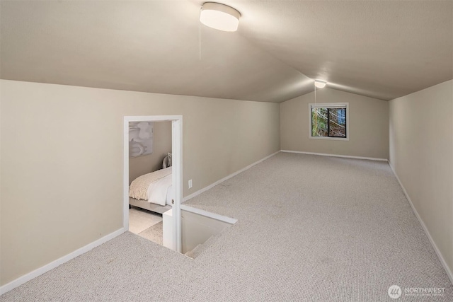 additional living space featuring baseboards, lofted ceiling, and carpet floors