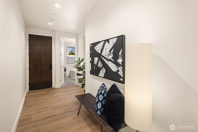 corridor featuring light wood finished floors, baseboards, and recessed lighting