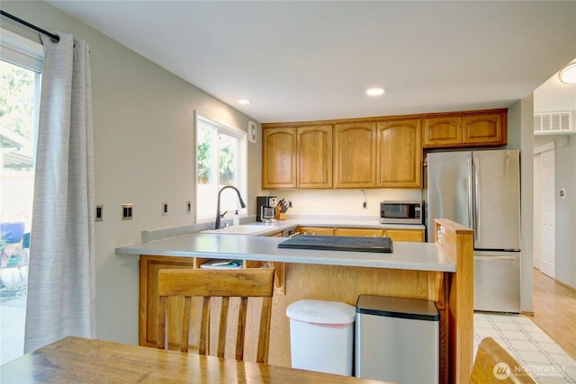 kitchen with visible vents, a breakfast bar, a sink, stainless steel appliances, and light countertops