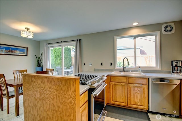 kitchen featuring visible vents, a sink, appliances with stainless steel finishes, a peninsula, and light countertops