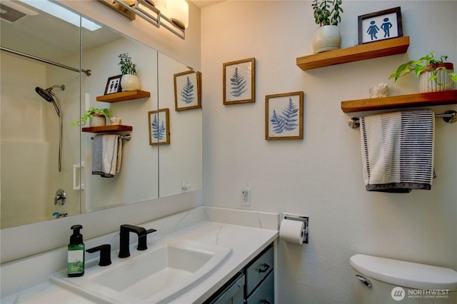 bathroom with visible vents, toilet, vanity, and walk in shower