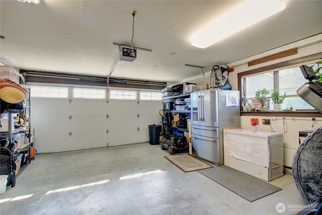 garage featuring refrigerator, a garage door opener, and stainless steel refrigerator with ice dispenser