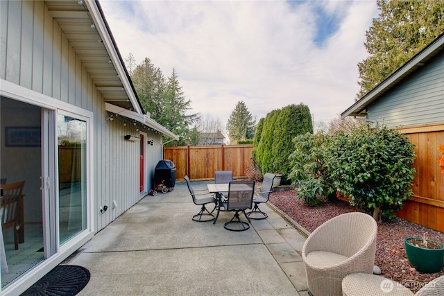 view of patio with outdoor dining area, a fenced backyard, and grilling area