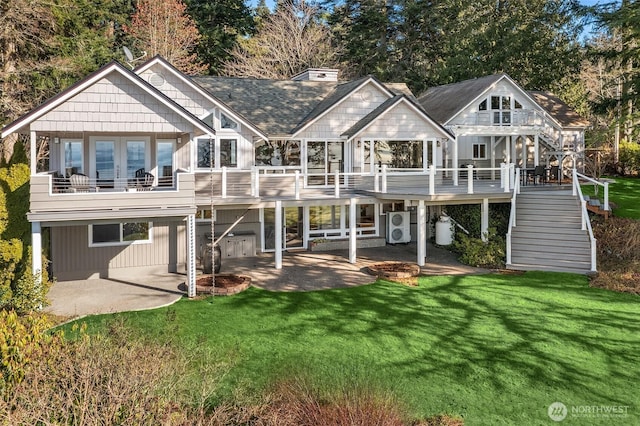 back of property with a yard, roof with shingles, a patio, and stairway