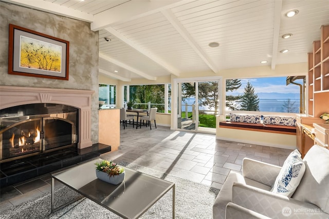 interior space featuring vaulted ceiling with beams, a glass covered fireplace, and wood ceiling