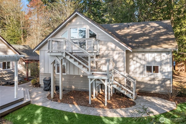 back of property featuring a shingled roof, stairway, board and batten siding, a deck, and a pergola