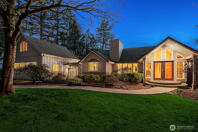 rear view of property with a chimney, french doors, a yard, and driveway