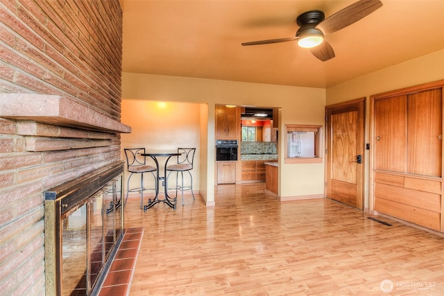 interior space with brown cabinets, visible vents, light wood-style flooring, a large fireplace, and oven