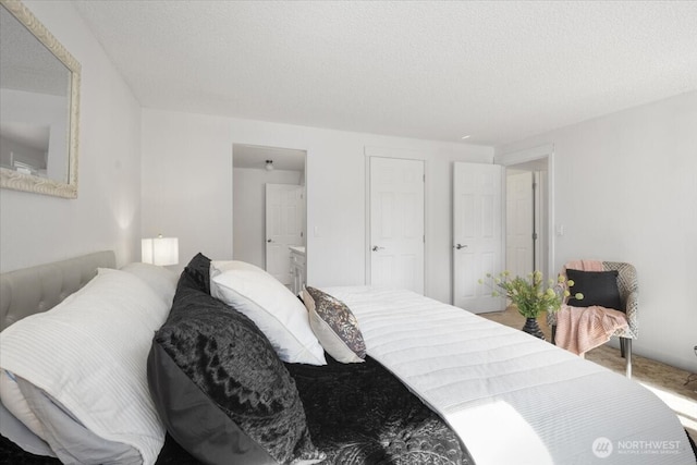 bedroom with a textured ceiling and ensuite bath