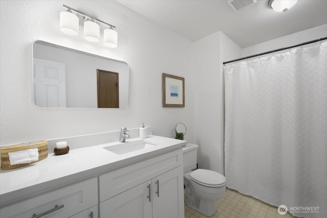 bathroom featuring toilet, vanity, visible vents, and tile patterned floors