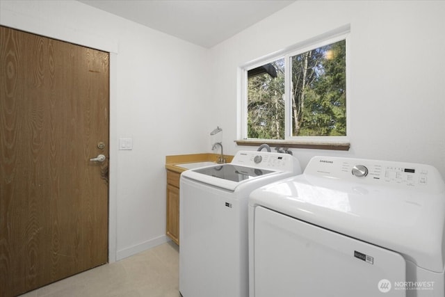 clothes washing area with cabinet space, baseboards, a sink, and washing machine and clothes dryer