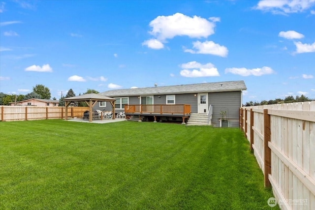 back of house featuring a fenced backyard, a yard, a deck, and a gazebo