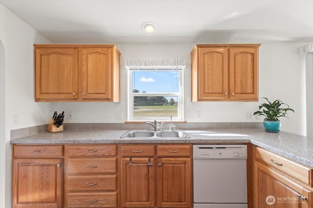 kitchen with white dishwasher, light countertops, and a sink