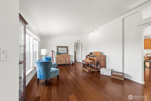 living area with track lighting, arched walkways, and wood finished floors