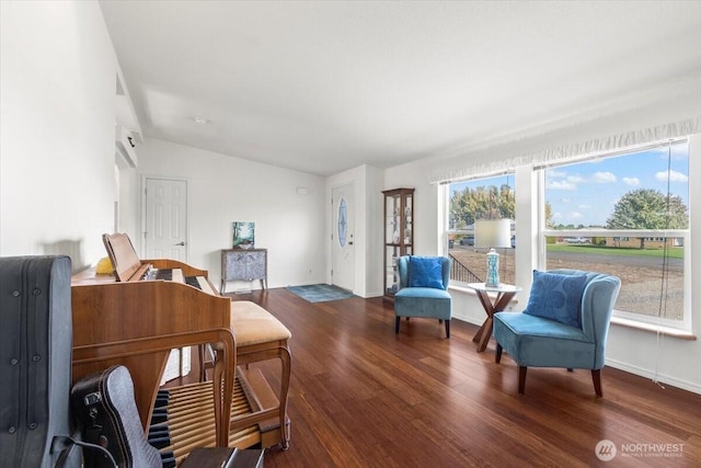 living area featuring vaulted ceiling, baseboards, and wood finished floors