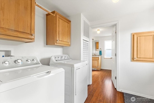 clothes washing area featuring dark wood-type flooring, independent washer and dryer, cabinet space, and baseboards