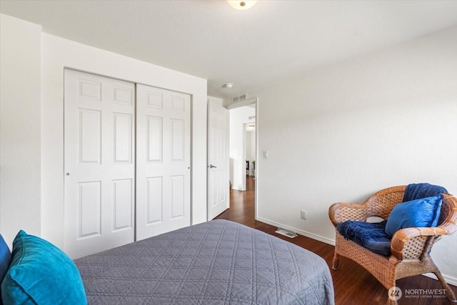 bedroom with dark wood-style flooring, a closet, visible vents, and baseboards