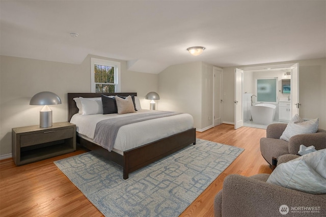 bedroom featuring baseboards, ensuite bathroom, and light wood finished floors