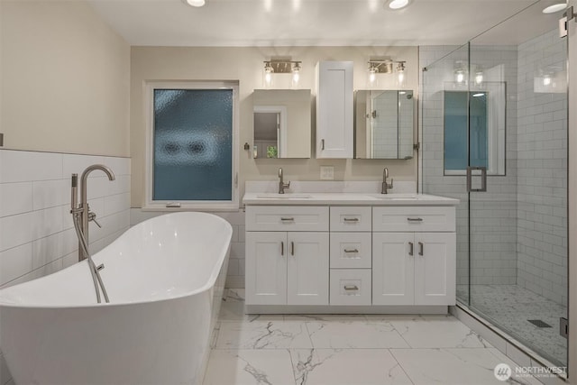 full bath featuring double vanity, marble finish floor, a stall shower, and a sink