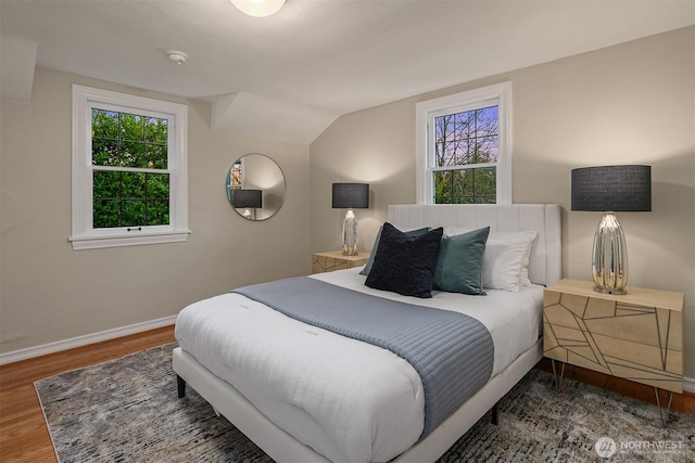 bedroom featuring baseboards, multiple windows, wood finished floors, and vaulted ceiling