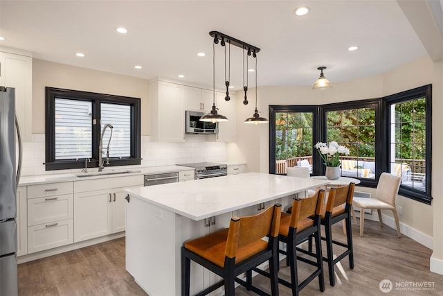 kitchen featuring white cabinetry, appliances with stainless steel finishes, a kitchen island, and a sink