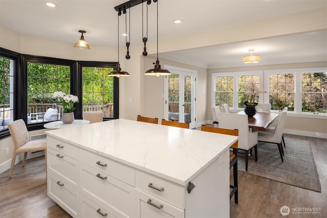 kitchen featuring dark wood finished floors, a center island, white cabinetry, french doors, and hanging light fixtures