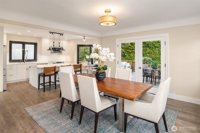 dining room featuring baseboards, plenty of natural light, wood finished floors, and french doors