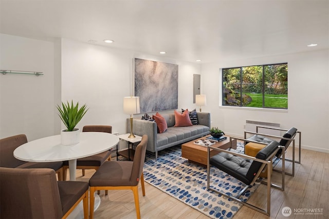 living area featuring electric panel, recessed lighting, light wood-type flooring, and baseboards