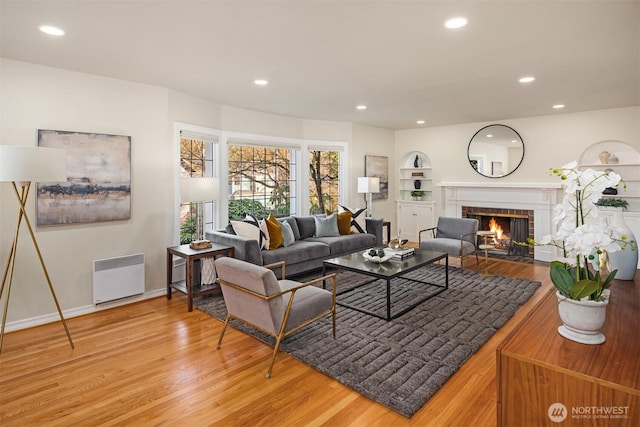 living room with recessed lighting, light wood-style flooring, a fireplace, and radiator heating unit