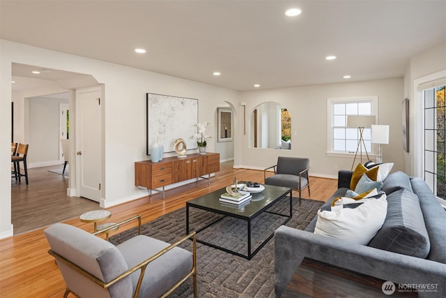 living area featuring recessed lighting, arched walkways, and wood finished floors