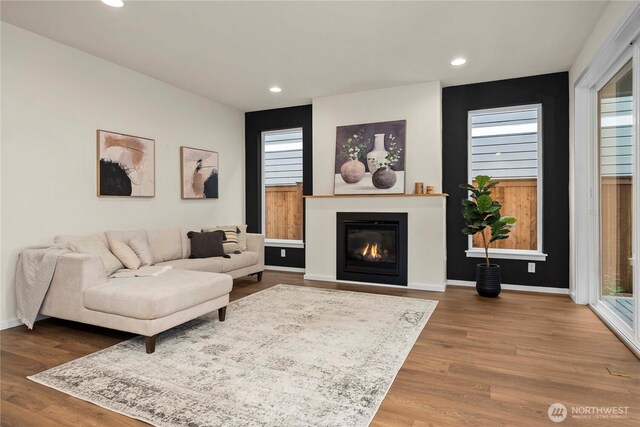 living room with a glass covered fireplace, baseboards, wood finished floors, and recessed lighting