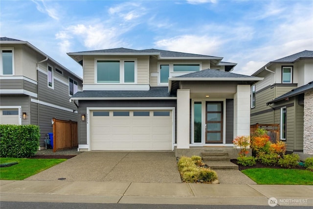 prairie-style home featuring an attached garage, concrete driveway, and roof with shingles