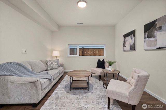 living room featuring dark wood-type flooring, visible vents, and baseboards