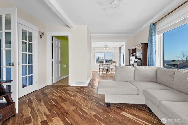 living room with baseboards, visible vents, ceiling fan, ornamental molding, and wood finished floors