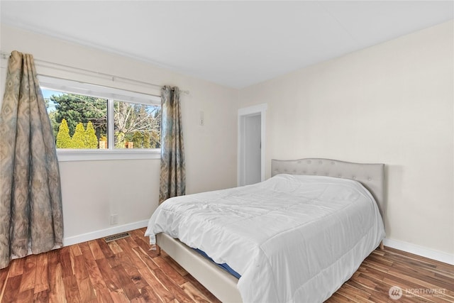 bedroom featuring wood finished floors, visible vents, and baseboards