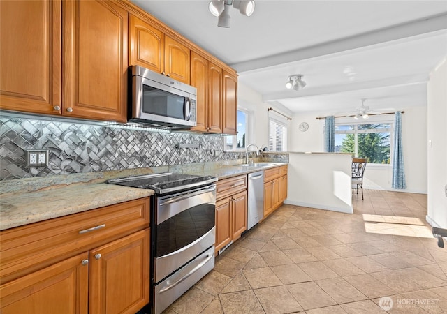 kitchen featuring stainless steel appliances, a sink, light stone countertops, tasteful backsplash, and beamed ceiling