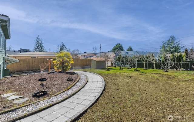 view of yard featuring an outbuilding, a fenced backyard, and a shed