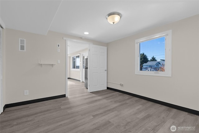 spare room featuring wood finished floors, visible vents, and baseboards