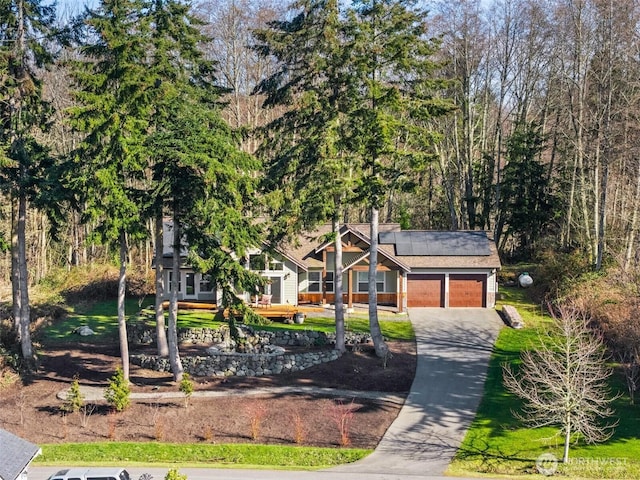 view of front of house with a garage, concrete driveway, and roof mounted solar panels