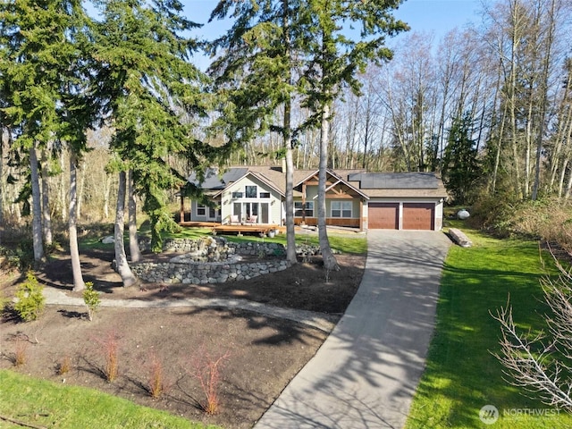 view of front facade with a garage, roof mounted solar panels, and concrete driveway