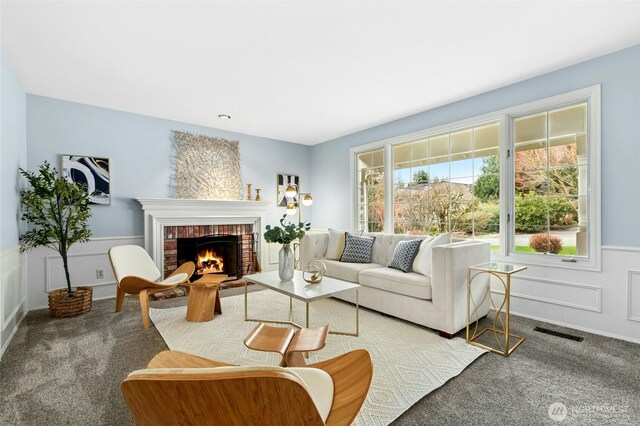 living area featuring visible vents, wainscoting, a fireplace, and carpet floors