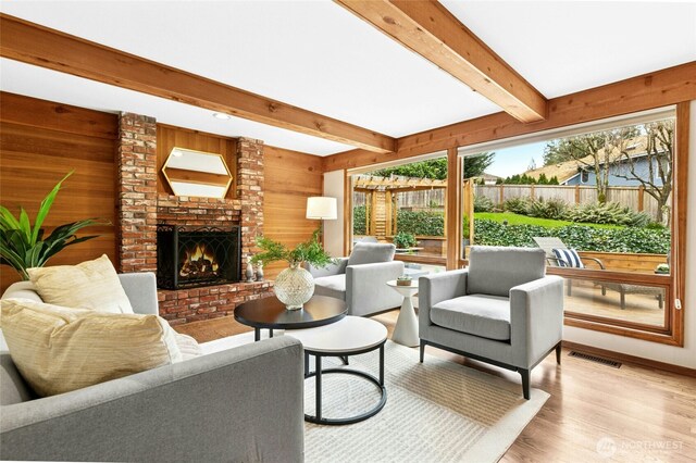 living room featuring visible vents, light wood-style flooring, a fireplace, and wooden walls