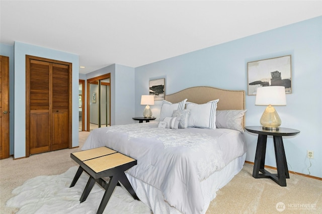 bedroom with baseboards, multiple closets, and light colored carpet