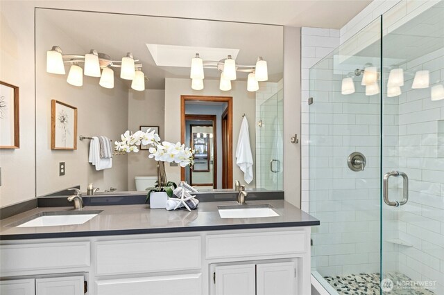 bathroom featuring a shower stall, double vanity, and a sink