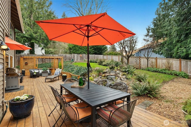 wooden terrace with outdoor dining area, a fenced backyard, and grilling area