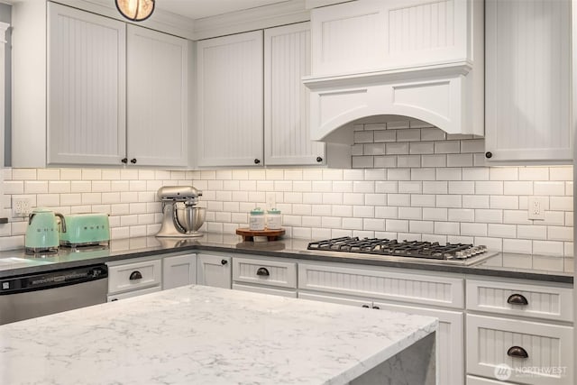 kitchen featuring appliances with stainless steel finishes, dark stone countertops, and decorative backsplash