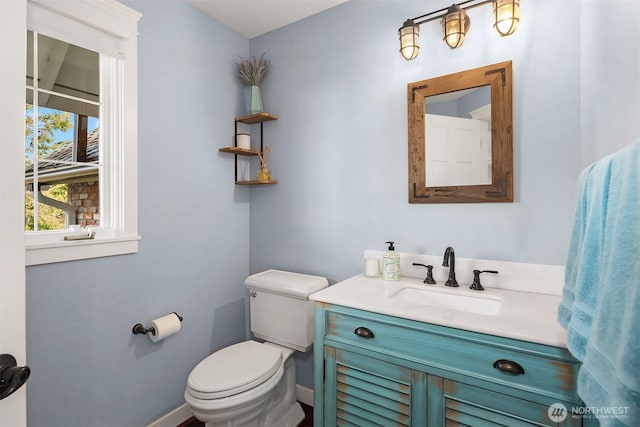 half bath with toilet, baseboards, and vanity